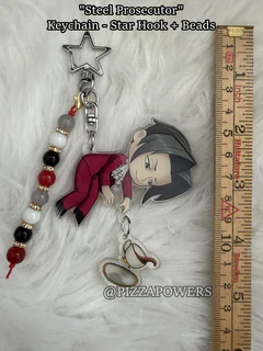 A chibi prosecutor in a red coat lying on his side, on a star hook with red and white beads